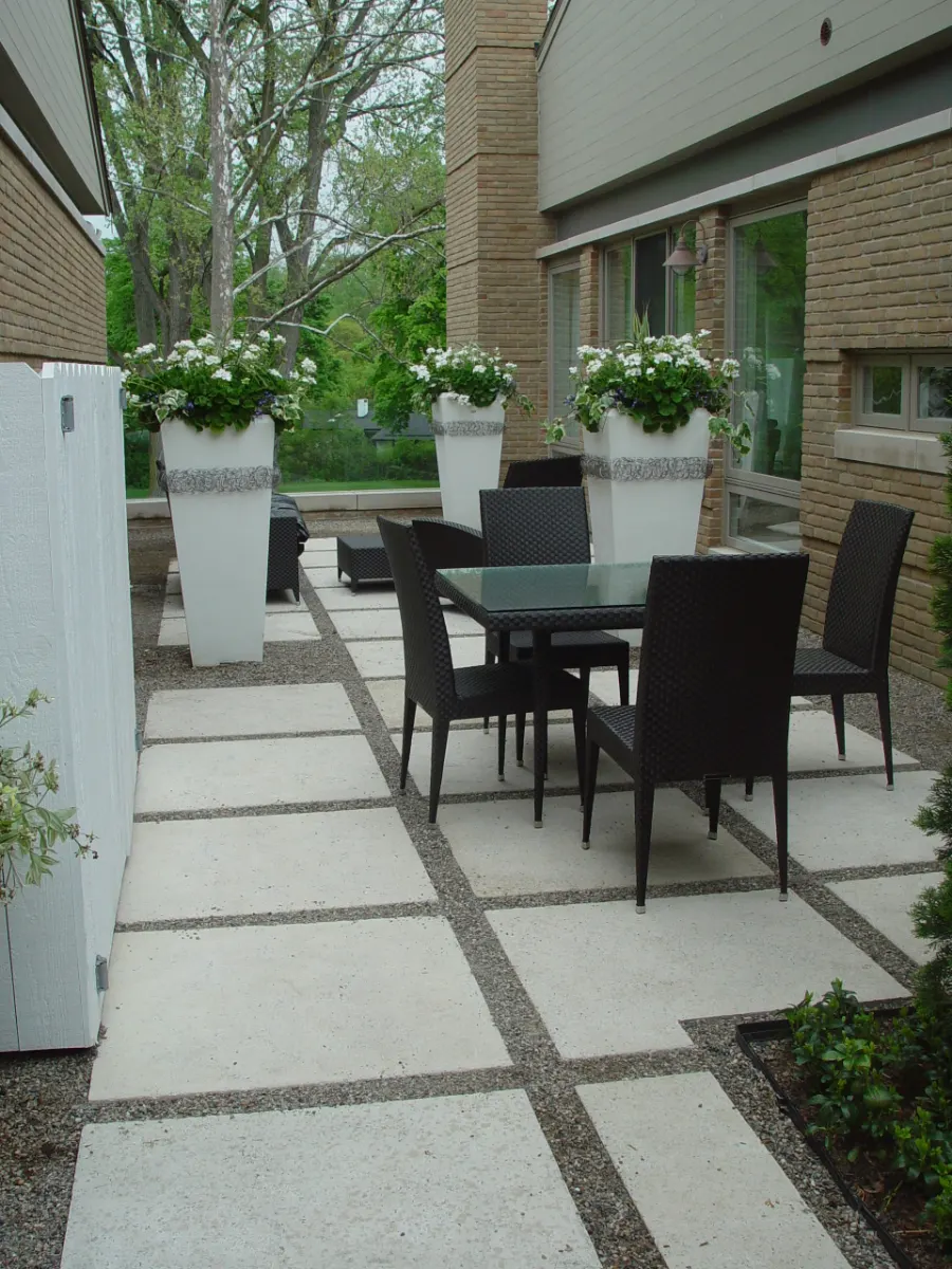 Concrete paver patio with gravel joints, outdoor dining set and white planters