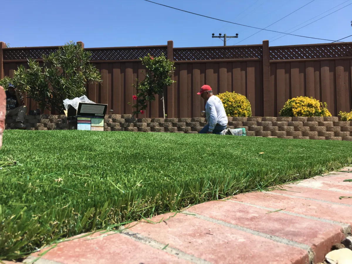 Golden Gate Landscaping crew laying new sod along a block retaining wall